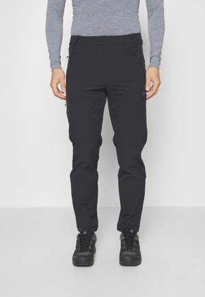 Black outdoor pants with a slim fit, made from lightweight fabric. Features zippered pockets and adjustable cuffs. Paired with black footwear.