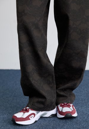 Pantaloni neri con motivo, realizzati in tessuto texturizzato, abbinati a sneakers atletiche a rete bianche e bordeaux con suola nera.
