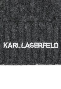 Gorro gris de punto hecho de material suave con textura acanalada. Presenta el logotipo blanco bordado "KARL LAGERFELD" en la parte frontal.
