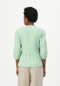 Πράσινο και λευκό ριγέ μπλούζα με τρία τέταρτα μανίκια, με συγκεντρωμένες λεπτομέρειες στη μέση και στρογγυλή λαιμόκοψη. Ελαφρύ ύφασμα.