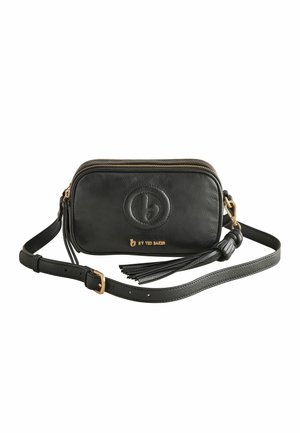 Czarna skórzana torba na ramię z regulowanym paskiem, złotym zamkiem błyskawicznym, ozdobą w postaci chwostu i wytłoczonym okrągłym logo z napisem "b by Ted Baker" z przodu.