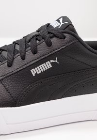 Sneaker in pelle nera con finitura texture, dotato di lacci neri, logo Puma bianco e suola bianca a contrasto.