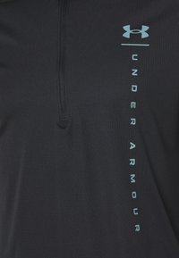 Černá sportovní mikina na zip s texturovaným povrchem. Vyznačuje se světle modrým logem "Under Armour" na pravé straně.