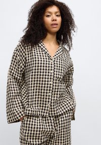 Μαύρο και μπεζ πουκάμισο με καρό μοτίβο, κουμπώματα, χαλαρή εφαρμογή, φαρδιά μανίκια και γιακά με εγκοπή, κατασκευασμένο από υφασμάτινη υφή.