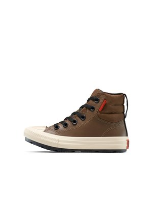 Baskets montantes marron avec lacets noirs, embout en caoutchouc et semelle crème contrastante. Présentent une tige texturée avec une étiquette d'accent rouge.