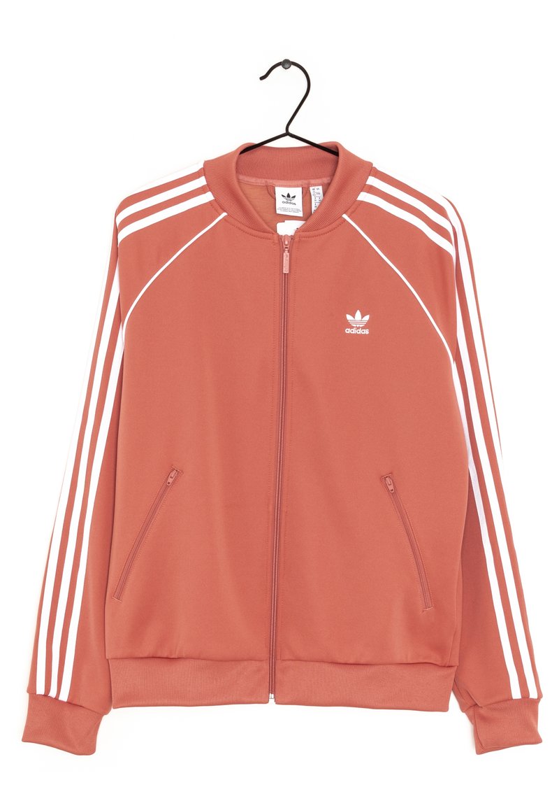 Adidas sportovní bunda v korálové barvě s bílými pruhy, plný zip vpředu, stojáček a dvě boční kapsy. Vyrobena z hladkého materiálu.
