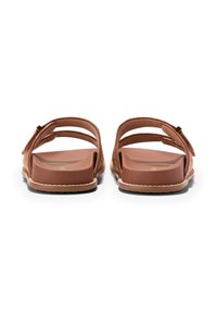 Bruna slip-on sandaletter med två breda remmar och en texturerad sula. Designen inkluderar en liten metallisk detalj på en rem.