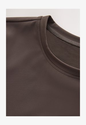 Braunes Sportshirt mit glatter Textur, Rundhalsausschnitt und dezenten Nahtdetails. Fokus auf Stoffzusammensetzung und Design.