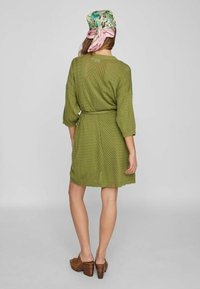 Robe vert olive à manches trois-quarts, tissu texturé, taille cintrée et motif à dessins. Comprend une écharpe fleurie en accent.