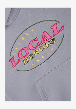 Gray sweatshirt featuring embroidered text "LOCAL" in red and "HEROES" in yellow, surrounded by green oval with yellow stars. Includes pouch pocket.
