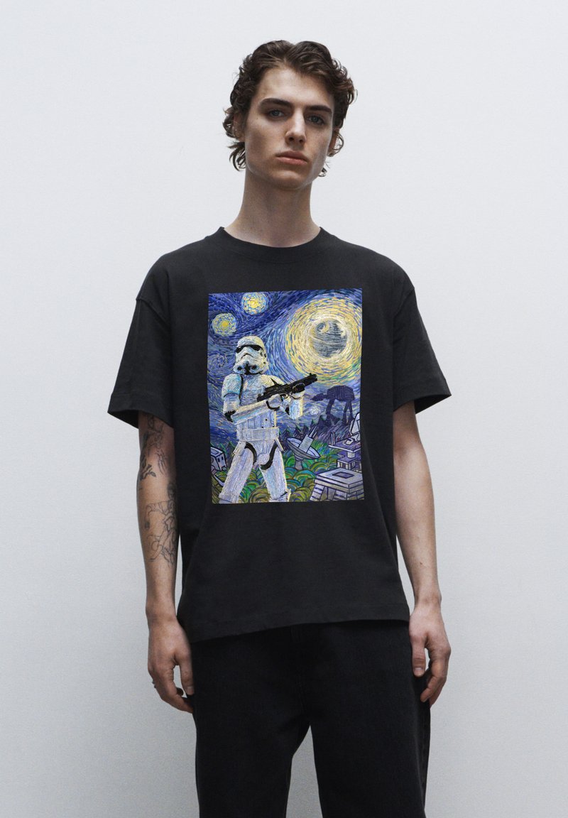 Camiseta negra de algodón con un gráfico impreso de un stormtrooper en una escena de noche estrellada, con colores vibrantes y texturas detalladas.