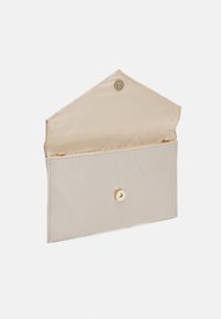 Pochette en beige slim avec fermeture à pression magnétique, ouverte pour montrer un intérieur lisse en satin et des bords cousus simples.