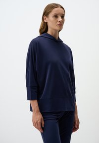 Felpa con cappuccio blu navy a maniche tre quarti, vestibilità ampia, texture morbida e orlo dritto, abbinata a pantaloni blu navy coordinati.