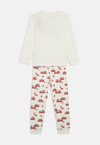 Ilgi piedurkņu krēmkrāsas tops ar mīkstu tekstūru, kas saskaņots ar baltiem pidžamas apakšiem, uz kuriem redzams krāsains ugunsdzēsēju automašīnu raksts un sarkanas akcenti.