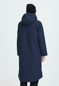 Cappotto lungo blu navy con cappuccio, realizzato in tessuto liscio. Presenta un taglio dritto, maniche lunghe e una leggera lucentezza.