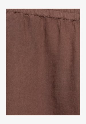 Ruskea kangas, jossa kerätty kuminauhavyötärö, näyttää tekstuurin ja hienot tikkausyksityiskohdat vyötärön saumassa.