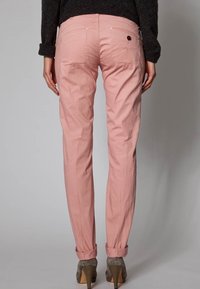 Ljust rosa byxor med slim fit, med uppvikta benslut, bakfickor och en liten logodetalj. Tillverkade av ett mjukt, slätt tyg.