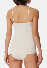 White cotton tank top with thin straps and a fitted design, paired with matching seamless underwear, showcasing a smooth texture.