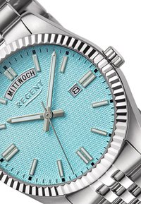 Montre en acier inoxydable argenté avec un cadran texturé bleu clair, des index horaires argentés, un affichage de la date et une lunette polie.