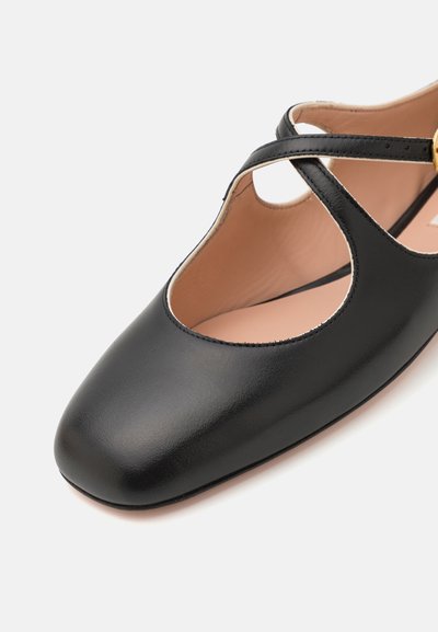 Bailarina de cuero negro con punta cuadrada, con correas entrecruzadas y un diseño recortado, textura suave y un interior ligero.