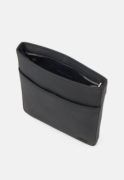 Housse d'ordinateur portable noire, texturée, avec une poche zippée, un intérieur lisse et une poche frontale extérieure. Forme rectangulaire, design minimaliste.