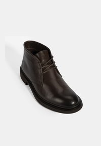 Bottines en cuir marron avec une finition lisse, bout rond, design minimaliste et fermeture à lacets classique. Semelle en caoutchouc pour la durabilité.