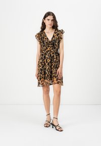Leopard print dress with a deep V-neck and ruffled sleeves. Sheer fabric, knee-length, with a relaxed fit. Black strappy sandals.