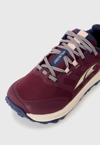 Bordeaux treningssko med mesh-overdel, strukturert detaljering, reflekterende aksenter og beige mellomsåle. Har grå lisser og en marineblå krage.
