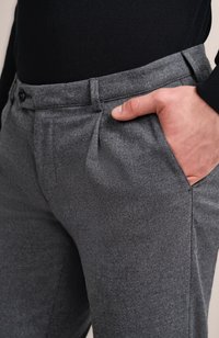 Graue Hose mit strukturiertem Finish, mit einem einzelnen vorderen Faltenwurf und seitlichen Taschen, gehalten von einem Taillenbund mit zwei schwarzen Knöpfen.