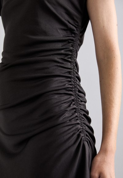 Black, sleeveless dress featuring gathered texture on the side, creating a draped effect. Smooth fabric with subtle sheen visible.