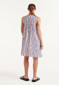 Abito senza maniche con un motivo a righe blu e bianche, decorato con disegni di conchiglie rosse e stelle marine. Il tessuto sembra leggero e traspirante.