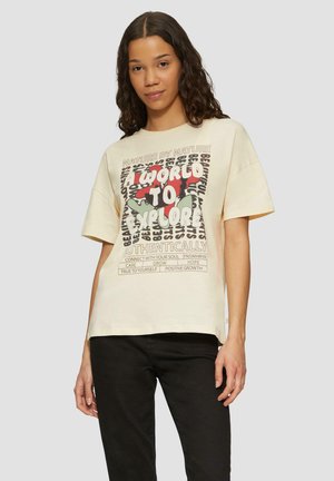 Crème-kleurig oversized t-shirt met een grafisch ontwerp van tekst en abstracte vormen in rood en groen. Korte mouwen en ronde halslijn.