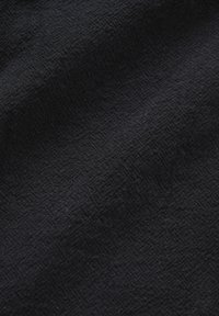 Tissu noir avec une texture fine tissée et des nervures diagonales subtiles qui créent un motif doux et légèrement en relief sur toute la surface.