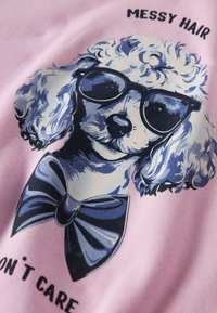 Tissu rose avec un motif représentant un chien à poils bouclés, portant des lunettes de soleil foncées et un nœud papillon bleu, accompagné du texte "MESSY HAIR DON'T CARE".