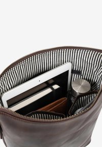 Braune Lederhandtasche mit gestreiftem Stoffinnenfutter, die ein Tablet, ein schwarzes Notizbuch, eine braune Geldbörse und eine Wasserflasche aus Edelstahl enthält.