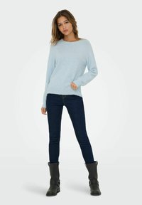 Light blue sweater with a round neckline and long sleeves, paired with dark skinny jeans and black ankle boots. Soft texture, casual design.