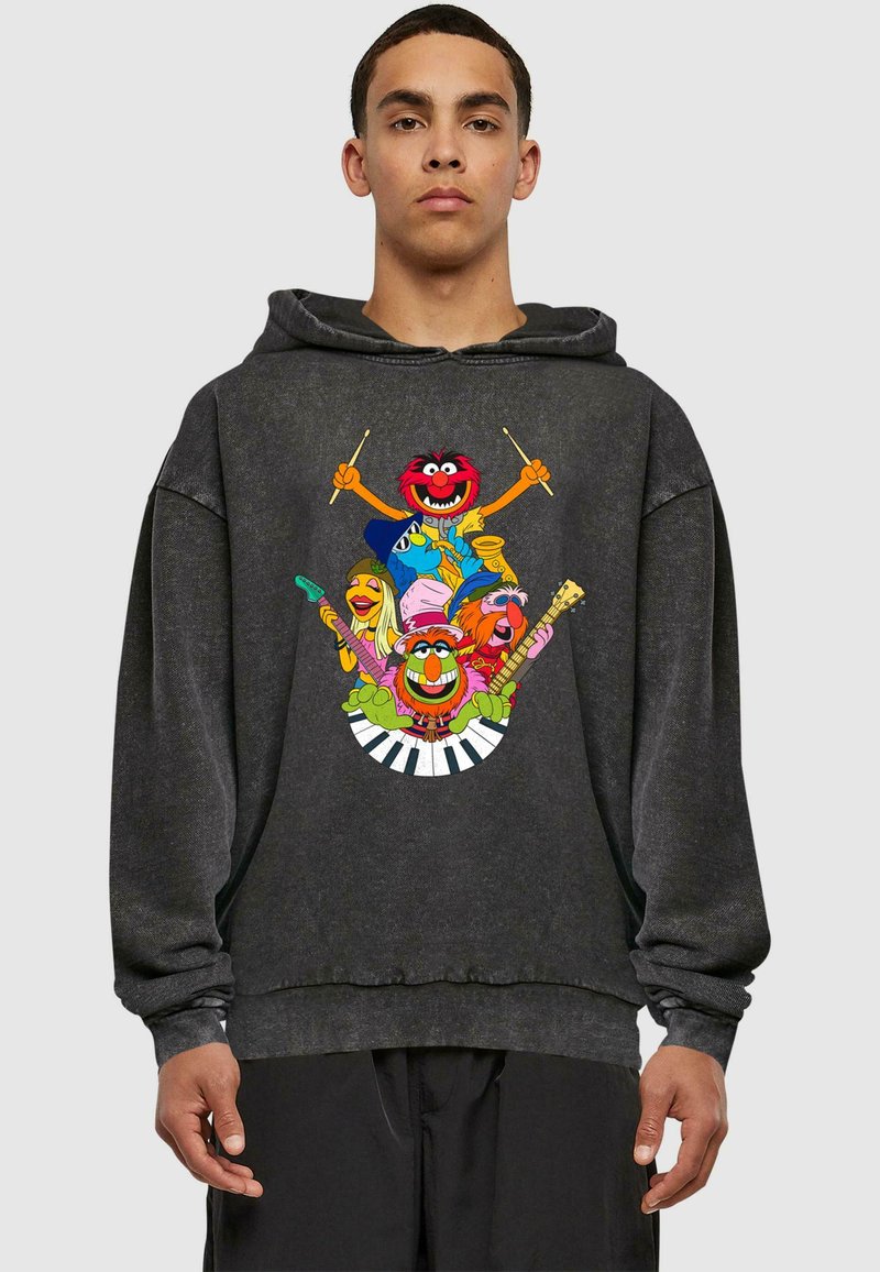 Sort oversized hoodie med et farverigt grafisk motiv af tegneseriefigurer, der spiller musikinstrumenter, sat mod en subtil slidtegn tekstur.