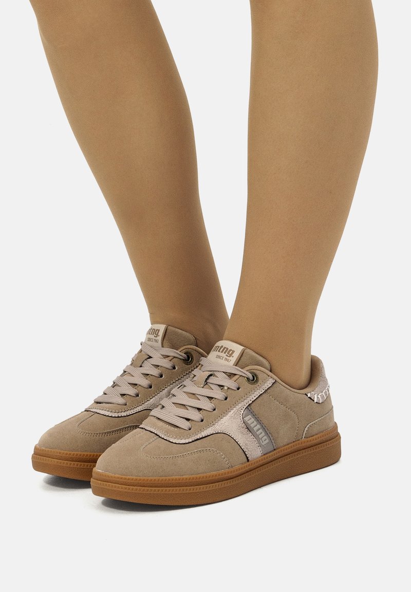 Sneaker beige in suede con suola in gomma e lacci piatti, caratterizzati da un design con pannello laterale e accenti con logo.