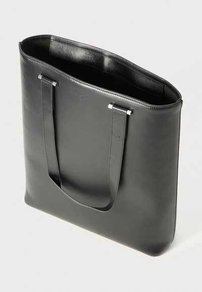 Schwarze Leder-Tote mit zwei langen Griffen, glatter Textur, offenem Design und subtiler Markenkennzeichnung auf der Vorderseite.