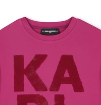 Fuksjowa koszula z okrągłym dekoltem, z dużymi, błyszczącymi czerwonymi cekinowymi literami tworzącymi napis "KARL". Gładka tekstura materiału, swobodny fason.