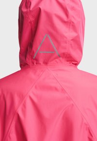 Veste imperméable rose vif avec capuche, avec un logo triangulaire réfléchissant minimaliste au dos de la capuche.