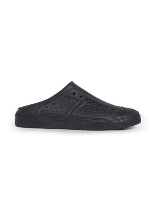 Zueco negro de goma tipo slip-on con lados perforados y sin talón, suela plana y agarre texturizado, mostrado en perfil lateral sobre fondo blanco.