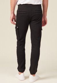Zwarte cargobroek met elastische manchetten, twee zijzakken en twee achterzakken. Gemaakt van een katoenmix, ontworpen voor een slim fit.
