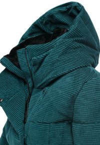 Teal huva jacka med en texturerad, våffelstickad tyg. Har dragkedjestängning, fickdetaljer och en mjuk svart inredning.