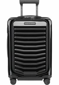 Maleta rígida negra con un acabado brillante, con surcos verticales, un asa retráctil y cuatro ruedas para facilitar su movilidad.