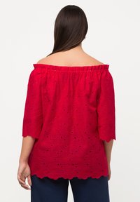 Rood geborduurd off-the-shoulder top met 3/4 mouwen, voorzien van bloemvormige uitsparingen en een golvende zoom. Katoenen stof biedt een ademende textuur.