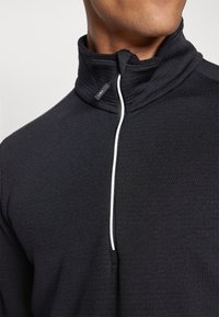 Pullover nero con zip al collo realizzato in tessuto morbido, con collo alto, zip bianca e un piccolo logo del marchio vicino al collo.
