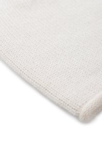 Tessuto lavorato a maglia bianco con una morbida texture, caratterizzato da un motivo sottile e uniforme e un bordo ripiegato. Il materiale appare caldo e leggero.