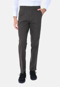 Pantaloni in cotone grigio scuro da uomo, vestibilità slim, frontale piatto, tasche laterali, chiusura con bottone e fondo con risvolto, abbinati a scarpe nere.