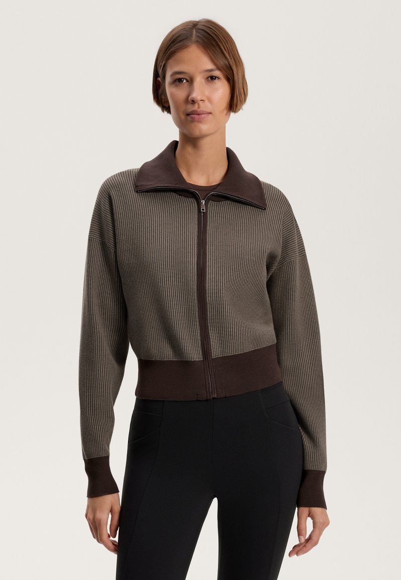 Brown and gray cropped zip-up sweater with ribbed texture, collar, and cuffed sleeves. Paired with black leggings.